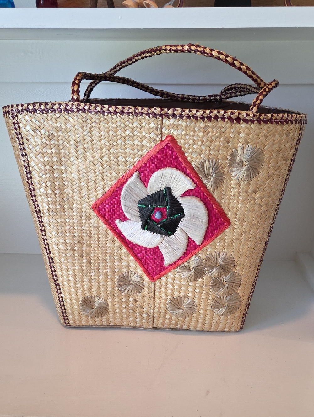 Vintage woven straw tote bag featuring an embroidered geometric floral design.
